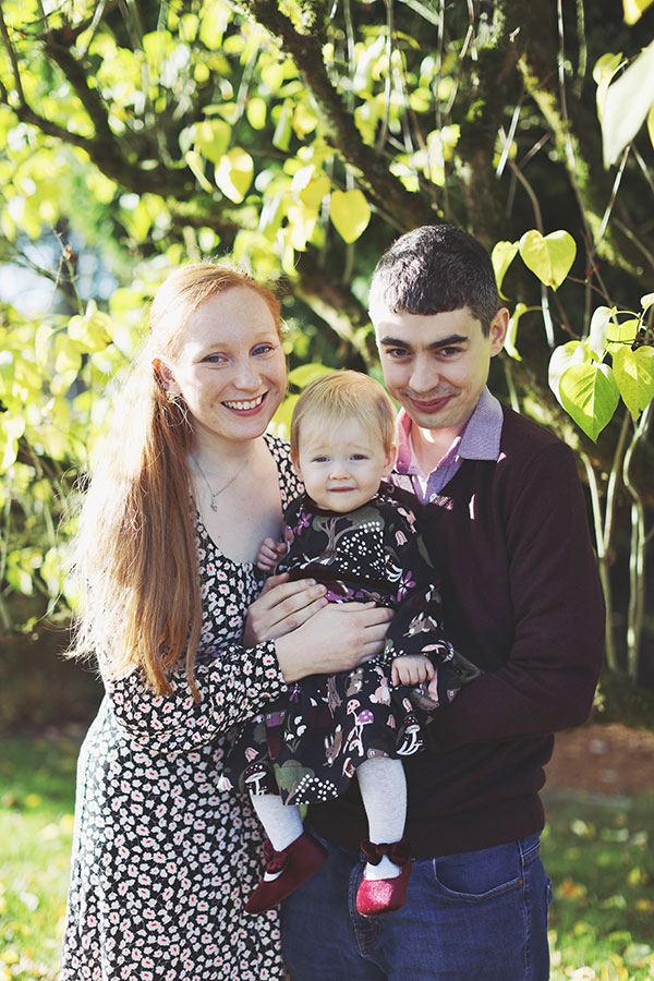 Baby in cosy dress surrounded by orange autumn leaves during outdoor birthday shoot in Derbyshire