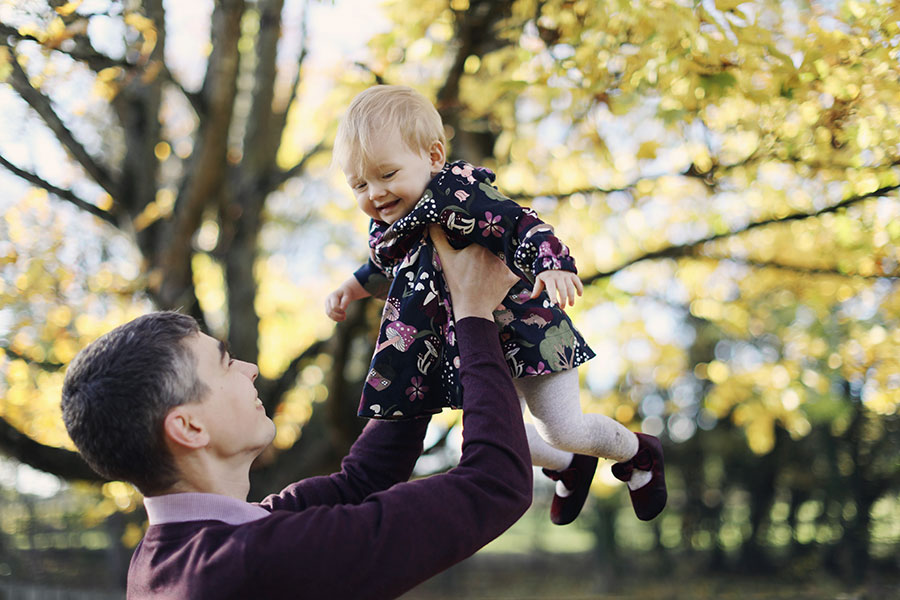 Dad holding one-year-old baby during outdoor first birthday photoshoot in Derbyshire