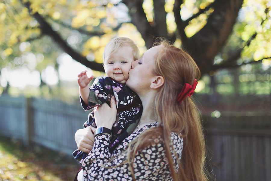 Mother holding one-year-old baby during outdoor first birthday photoshoot in Derbyshire