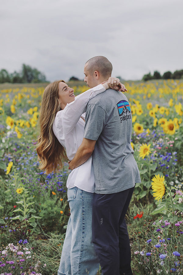 Ellie and Kamen laughing among sunflowers at Barlow Sunflower Field engagement photoshoot