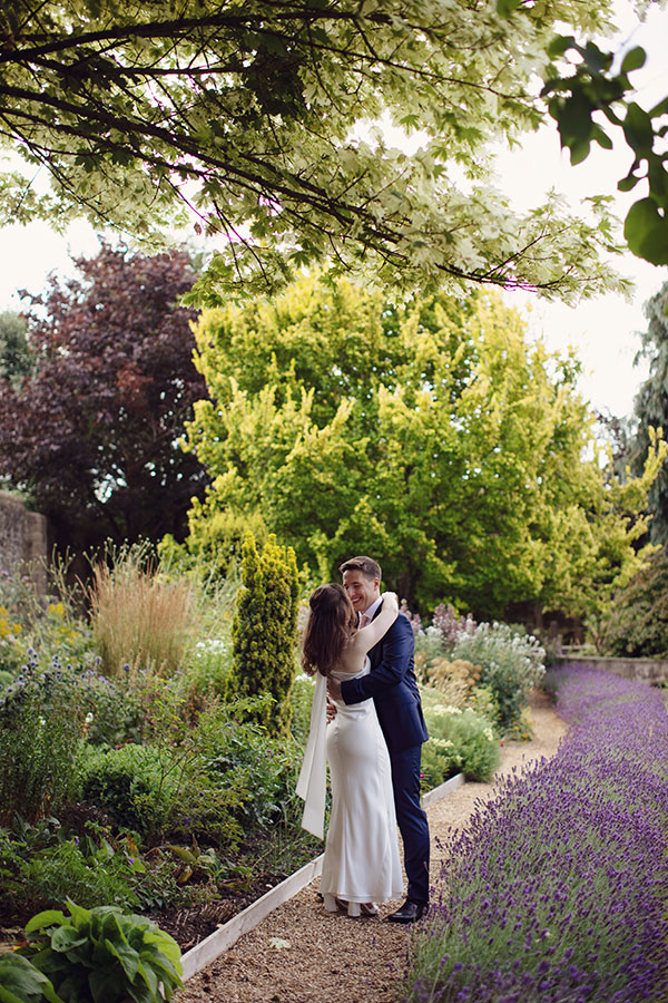 Bride and groom standing in the gardens during their Fisher’s Baslow Hall wedding — Derbyshire wedding photography.