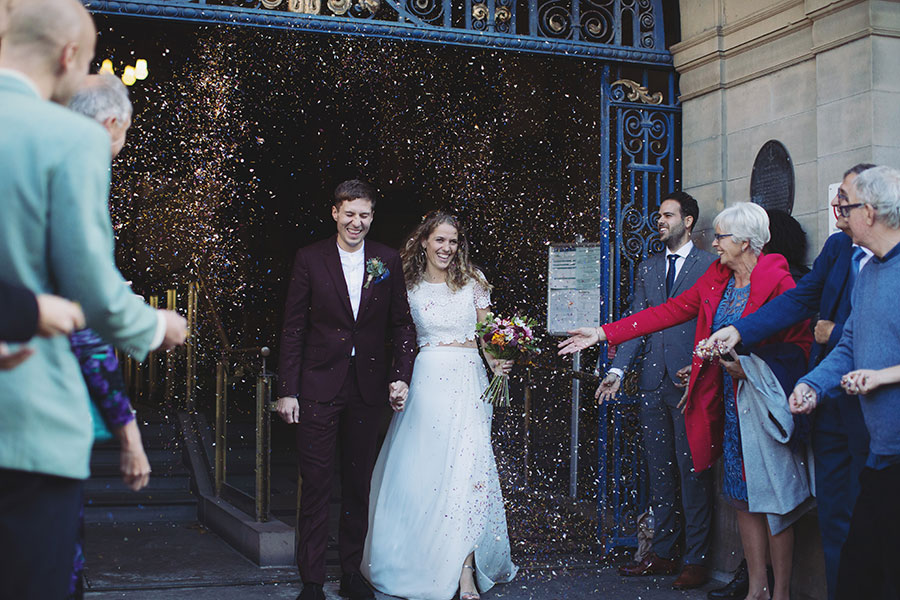 Newly married couple walking down the steps of Sheffield Town Hall as guests throw confetti