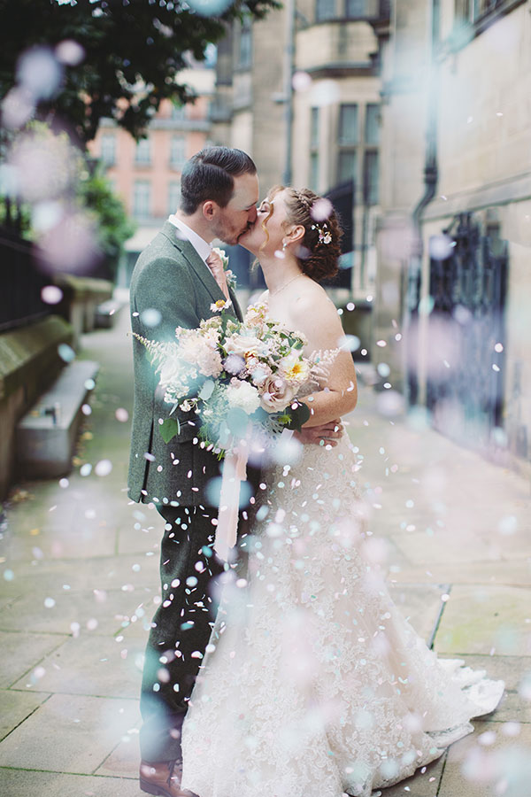 Newly married couple walking down the steps of Sheffield Town Hall as guests throw confetti