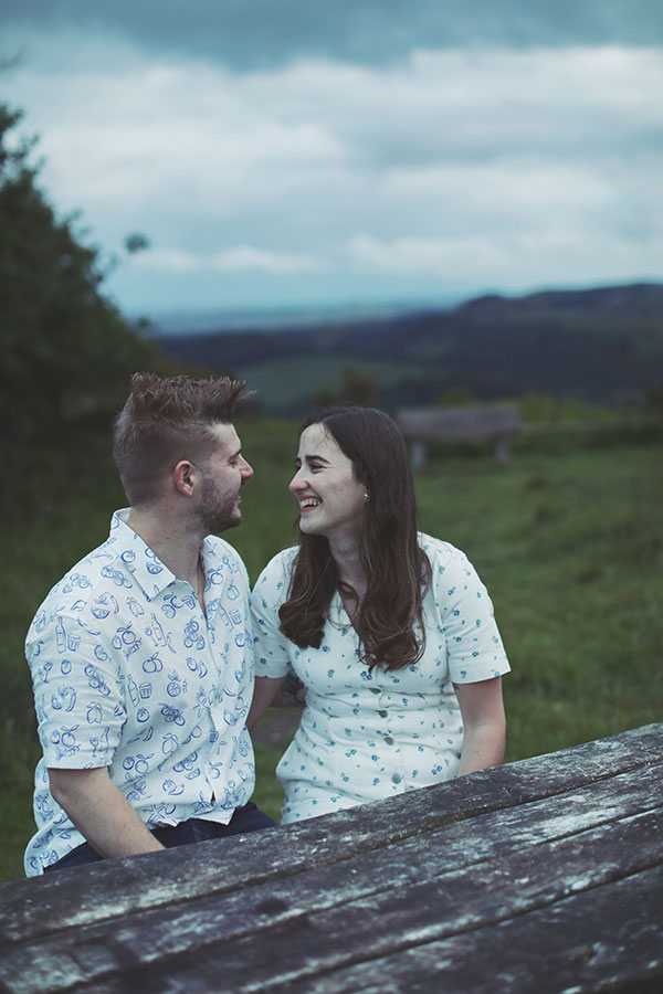 Diana & Alex ♡ Peak District Engagement Photoshoot 10 Diana and Alex holding hands on a hillside in the Peak District, with rolling countryside in the background.