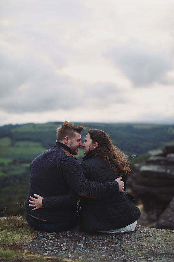 Diana & Alex ♡ Peak District Engagement Photoshoot 12 Diana and Alex holding hands on a hillside in the Peak District, with rolling countryside in the background.