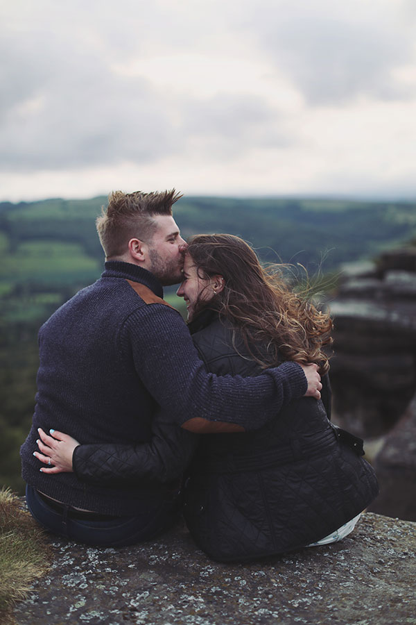 Diana & Alex ♡ Peak District Engagement Photoshoot 4 Diana and Alex standing close together in the Peak District, surrounded by green hills and ferns under an overcast sky.