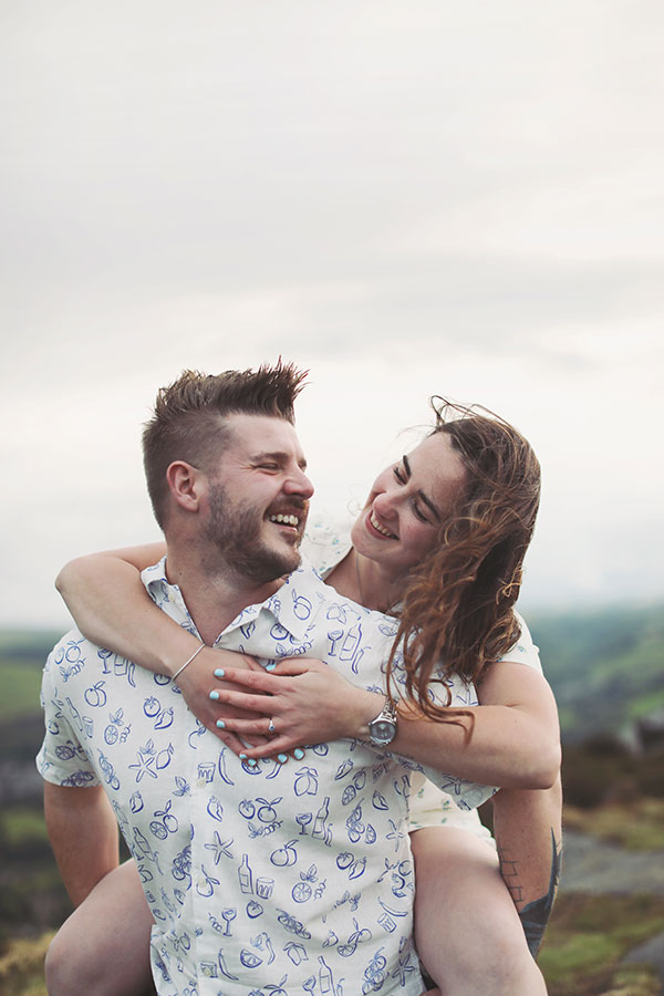 Diana & Alex ♡ Peak District Engagement Photoshoot 9 Diana and Alex holding hands on a hillside in the Peak District, with rolling countryside in the background.