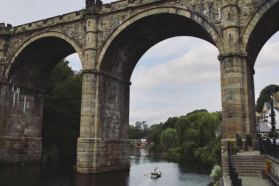 Couple rowing a boat on the River Nidd during a sunny Knaresborough engagement photoshoot.