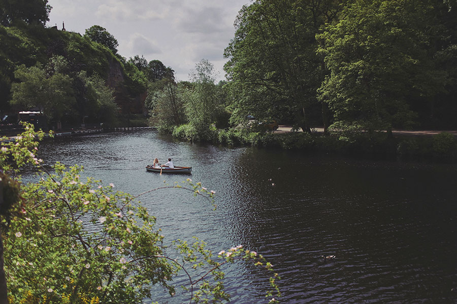 Couple rowing a boat on the River Nidd during a sunny Knaresborough engagement photoshoot.