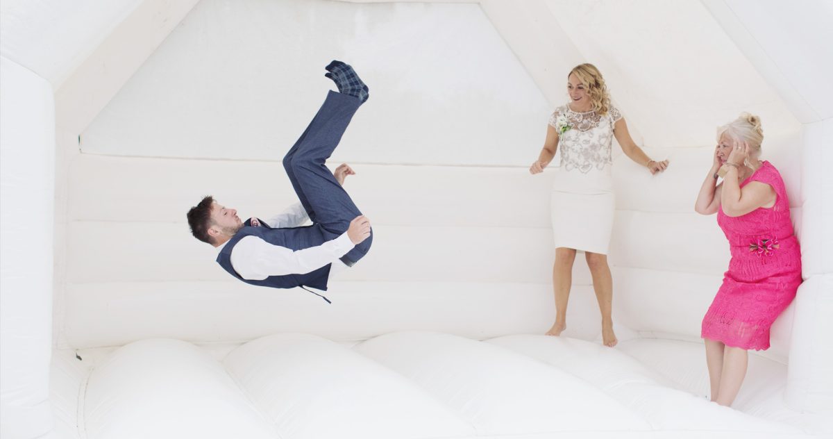 Fun wedding bouncy castle natural photography of man doing backflip
