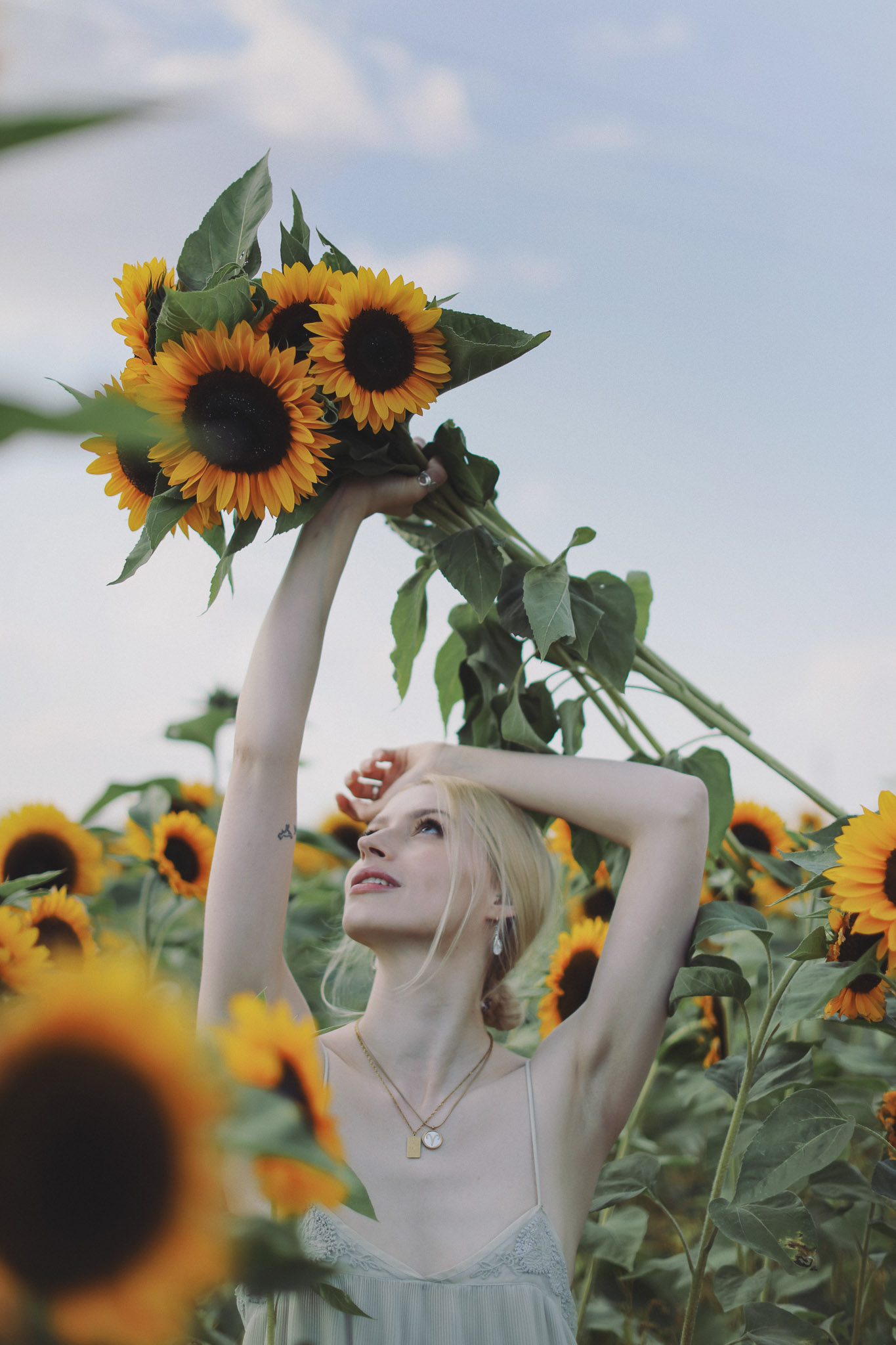 Portrait of a woman in a white dress surrounded by sunflowers in Barlow fields