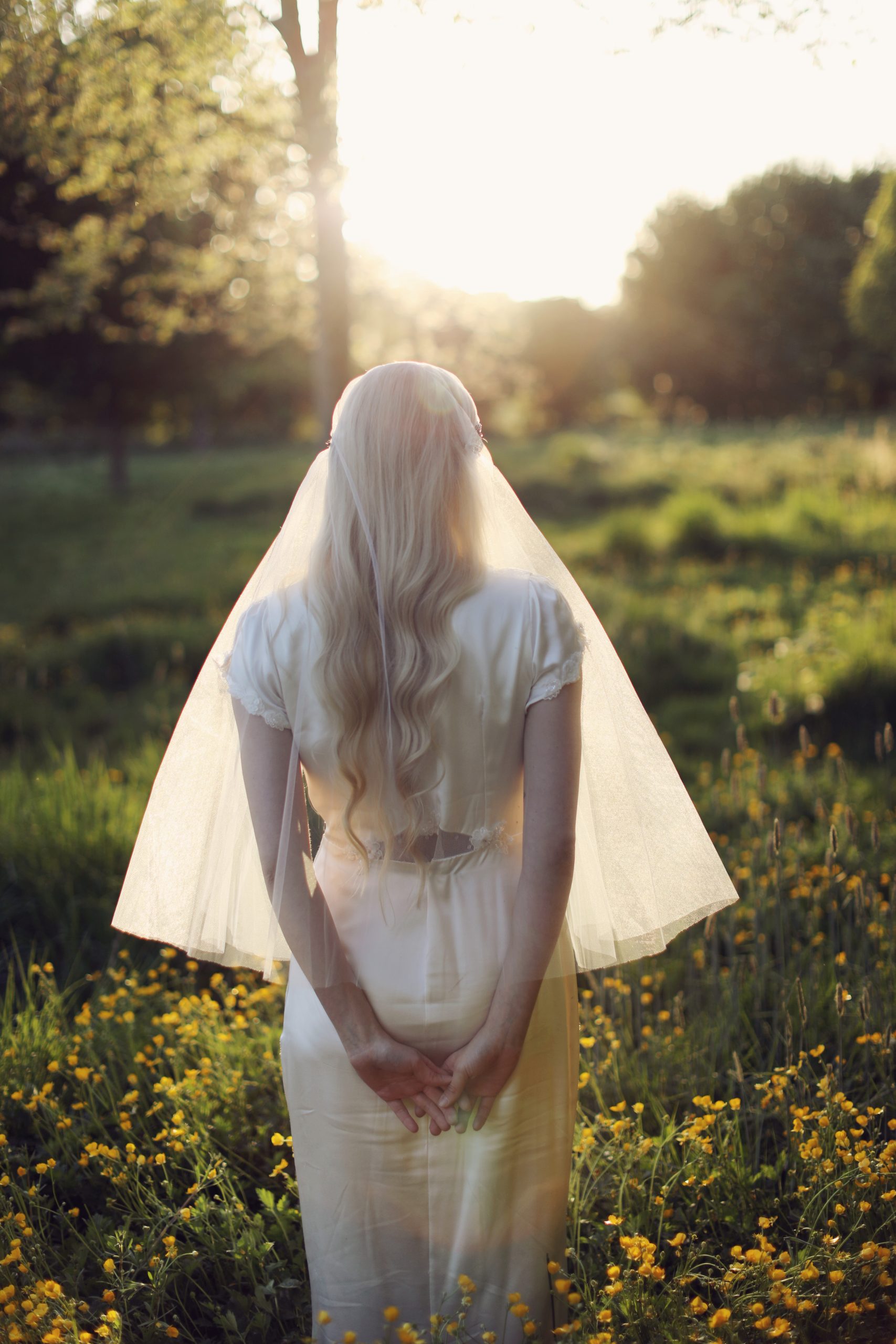 Romantic bride in a vintage-inspired wedding dress surrounded by tulips and warm sunset light