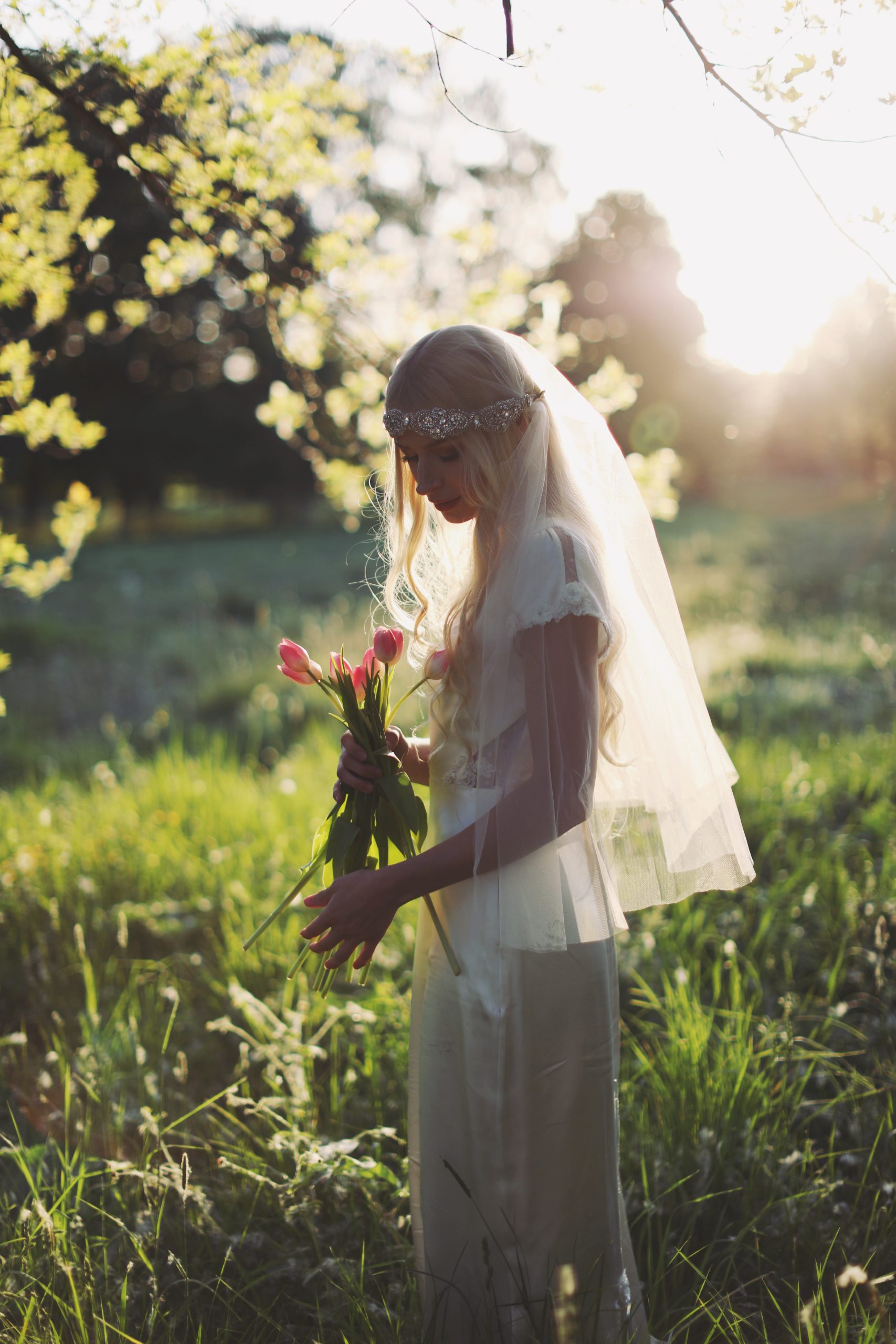 Romantic bride in a vintage-inspired wedding dress surrounded by tulips and warm sunset light