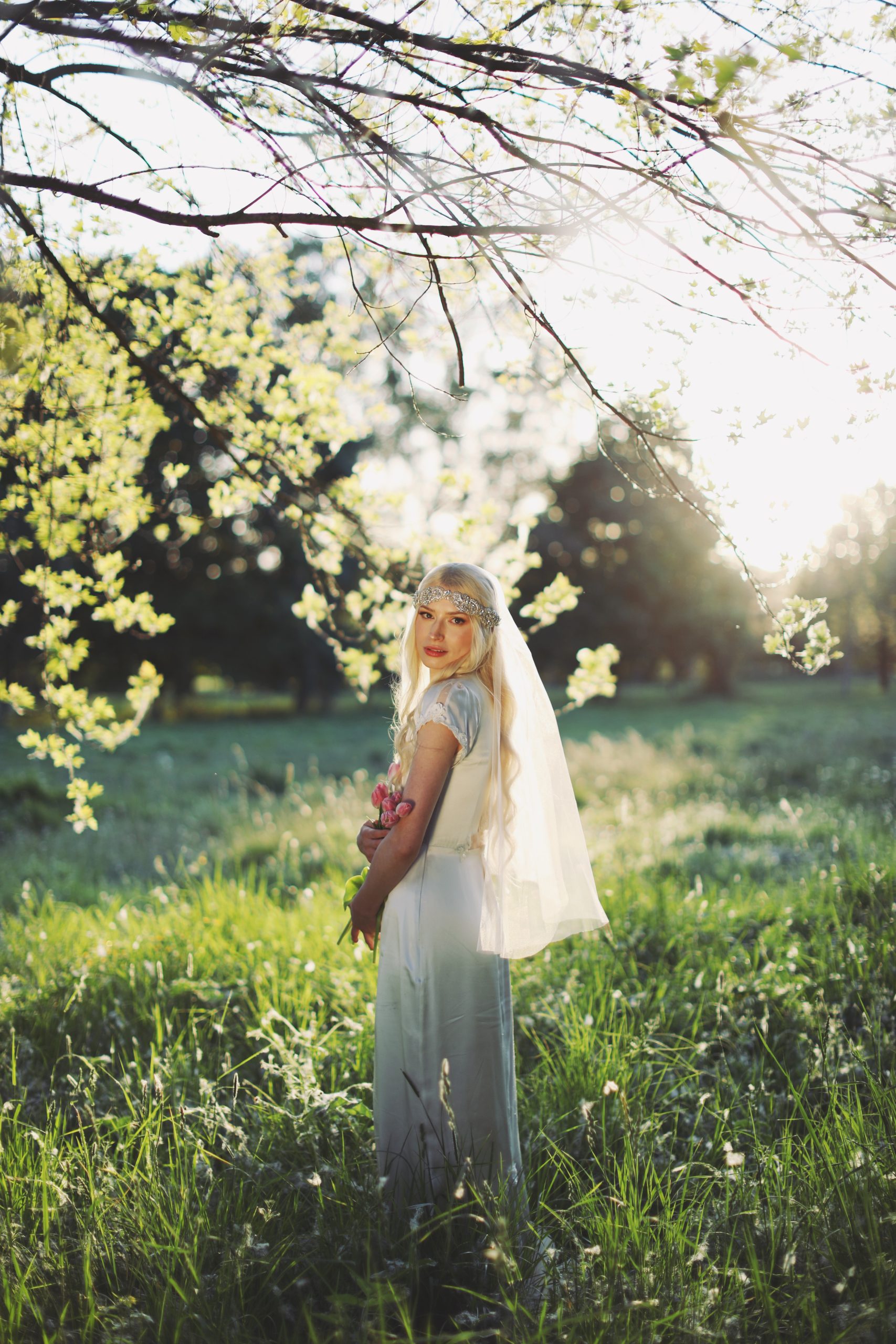Dreamy outdoor bridal portrait with soft veil, floral headpiece, and romantic garden setting