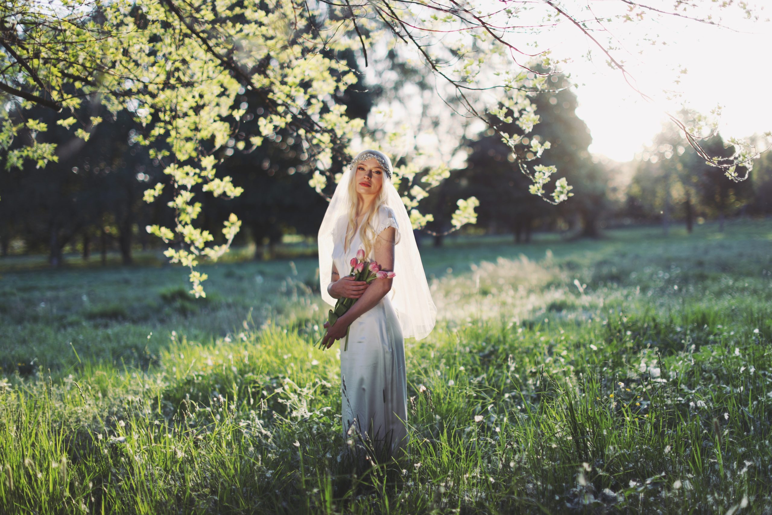 Dreamy outdoor bridal portrait with soft veil, floral headpiece, and romantic garden setting