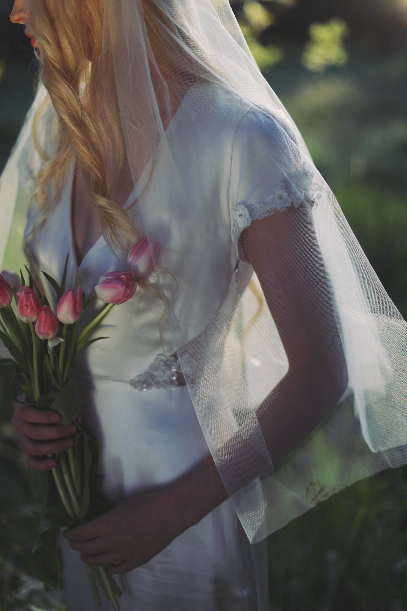 Dreamy outdoor bridal portrait with soft veil, floral headpiece, and romantic garden setting