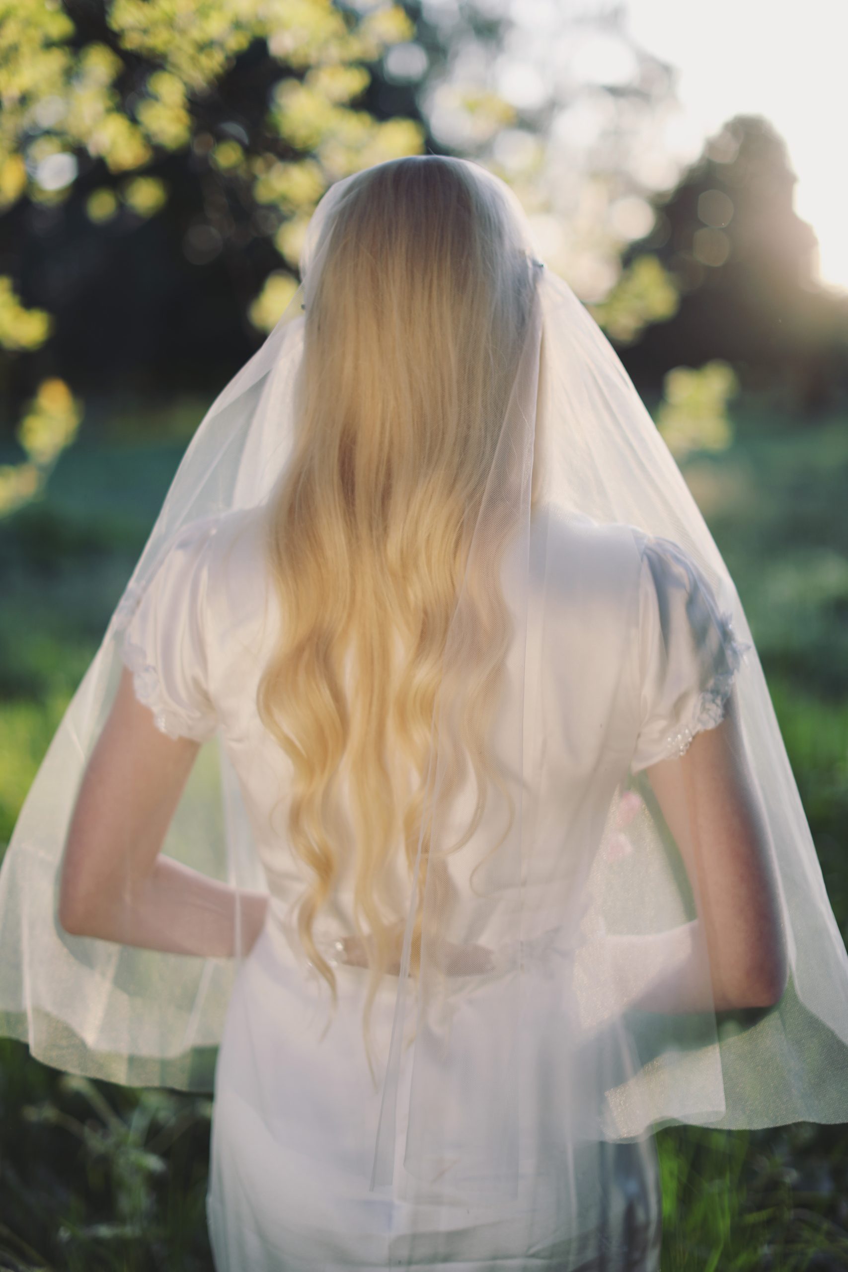 Dreamy outdoor bridal portrait with soft veil, floral headpiece, and romantic garden setting