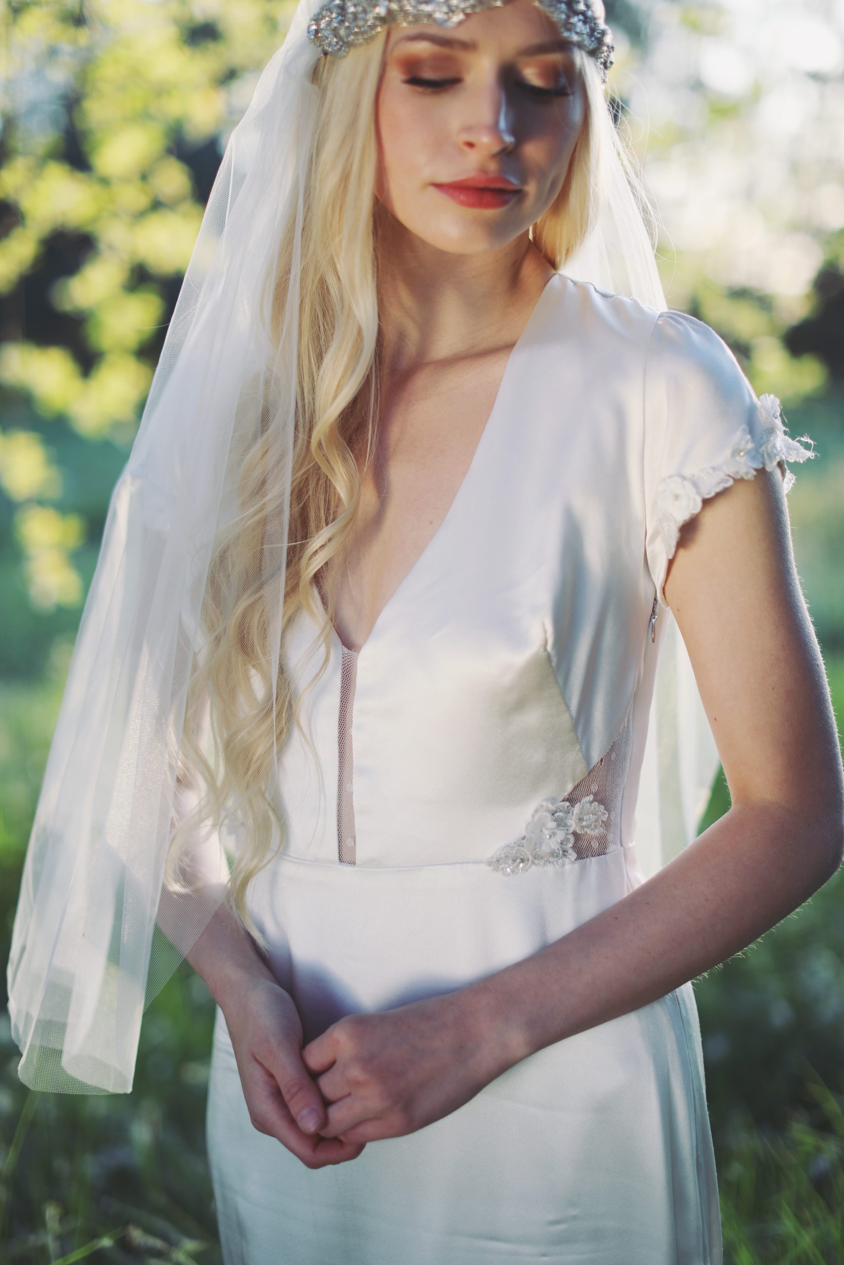 Dreamy outdoor bridal portrait with soft veil, floral headpiece, and romantic garden setting