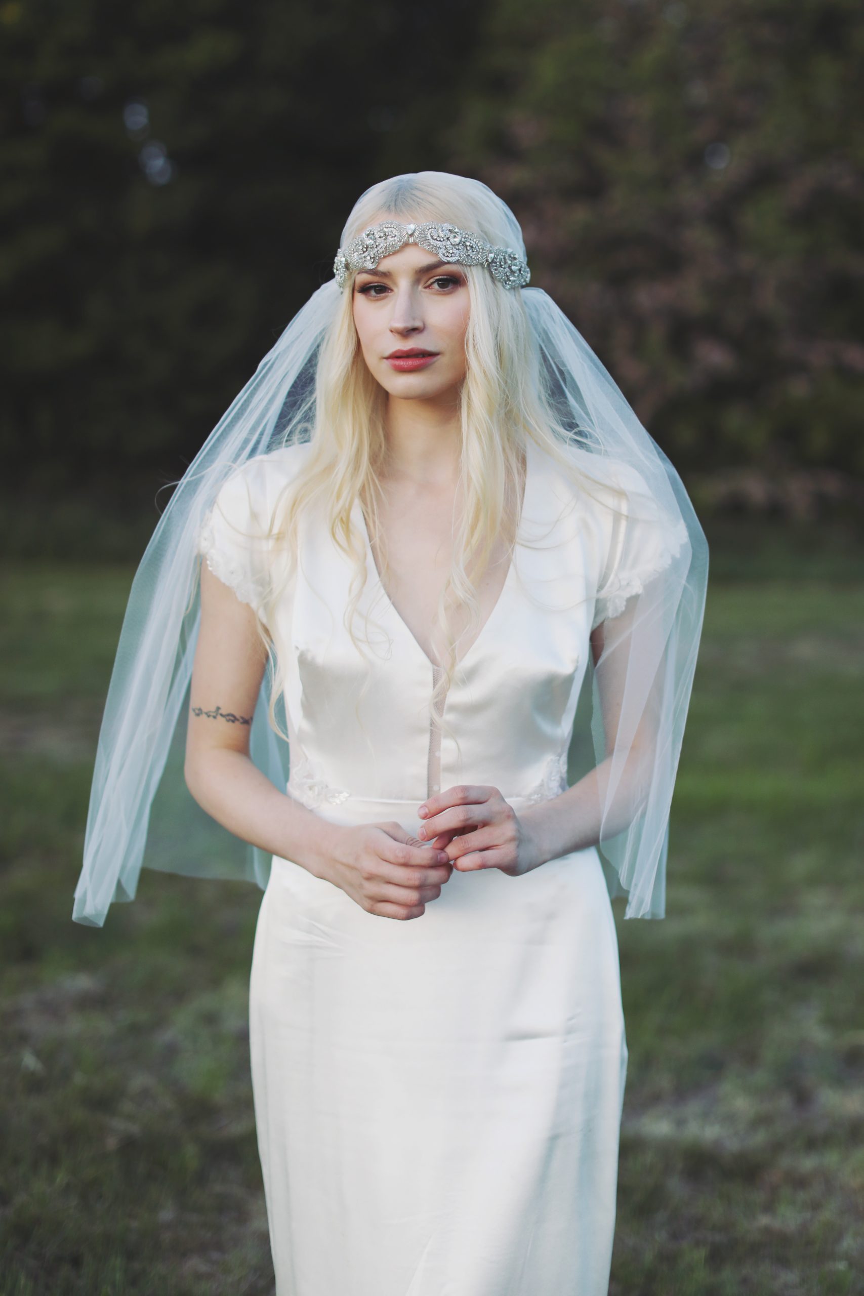 Ethereal bride in a lace wedding gown standing among blooming spring flowers at golden hour