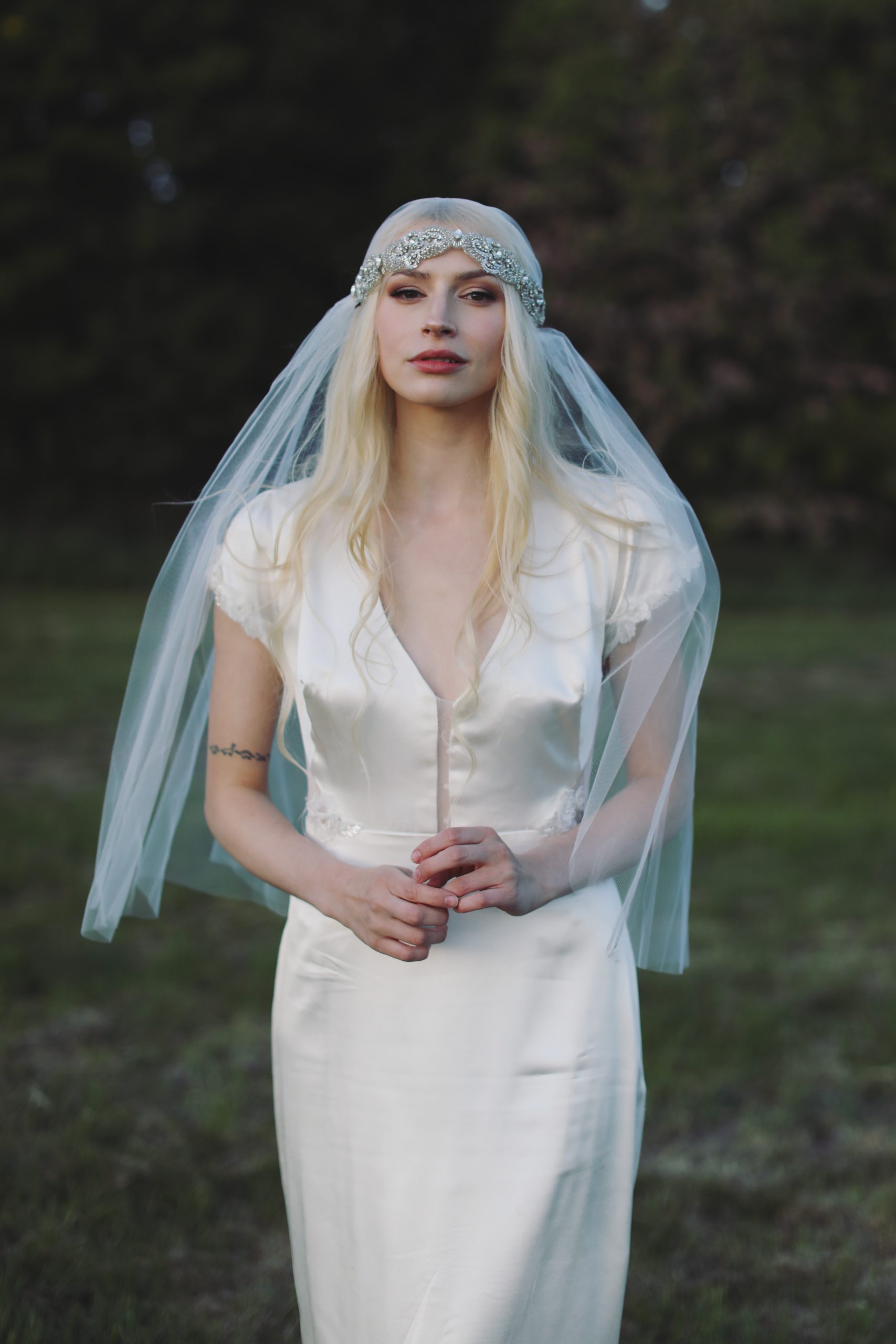 Ethereal bride in a lace wedding gown standing among blooming spring flowers at golden hour