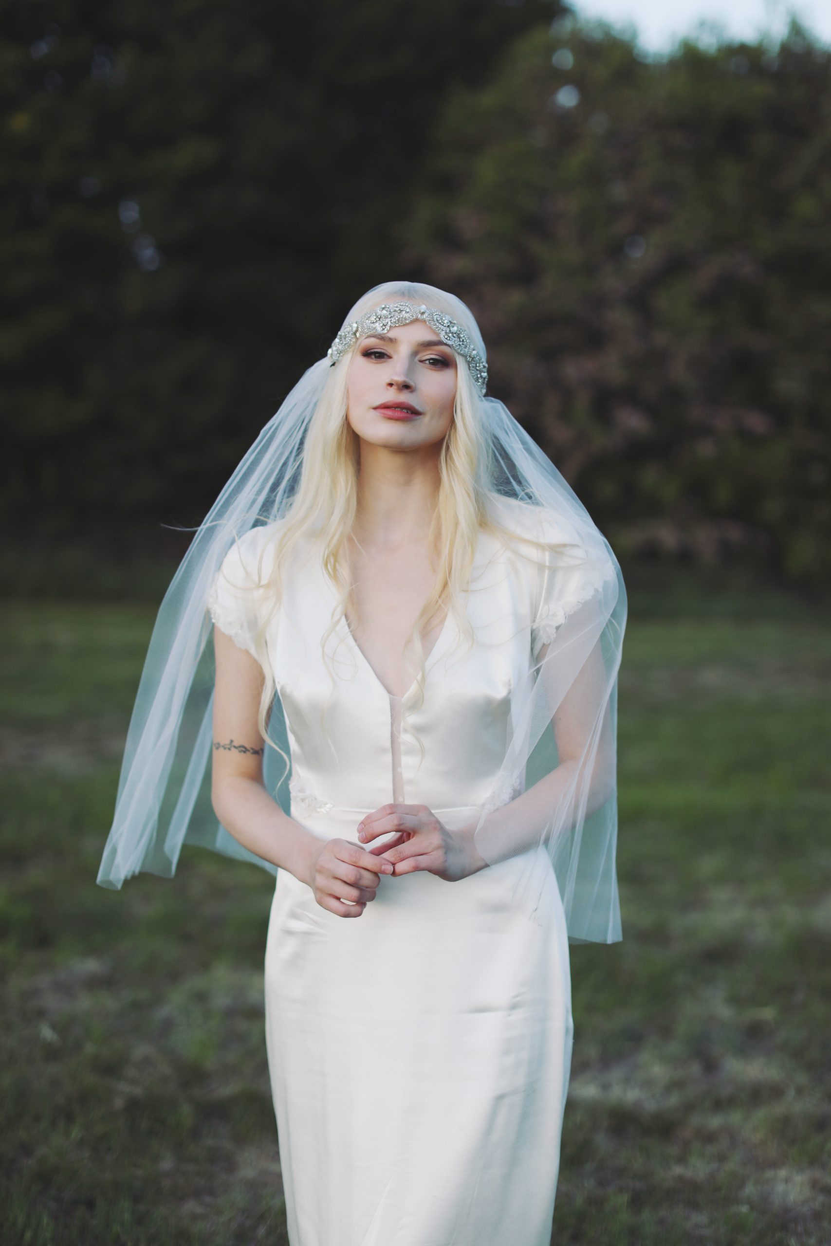 Ethereal bride in a lace wedding gown standing among blooming spring flowers at golden hour
