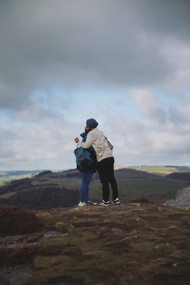 Wide landscape photograph of a couple standing together on a Peak District hillside