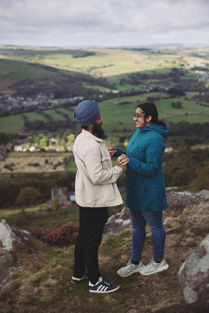 Newly engaged couple smiling and holding hands during a romantic Peak District photoshoot